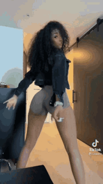 a woman with curly hair is dancing in a room .