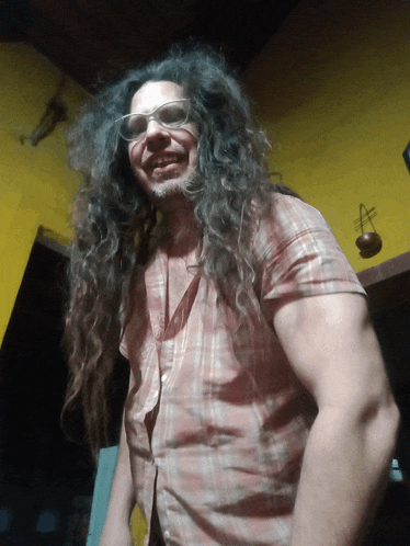 a man with long hair and glasses is smiling for the camera