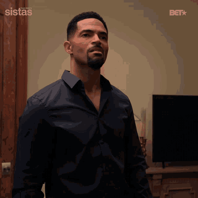 a man in a black shirt is standing in front of a television with a bet logo behind him