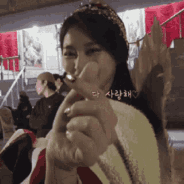 a woman is making a heart shape with her fingers and the word love is on the bottom left