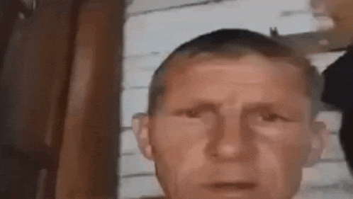 a man with a shaved head is looking at the camera with a serious look on his face .