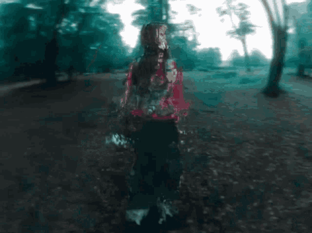 a girl in a red sweater is standing in a forest