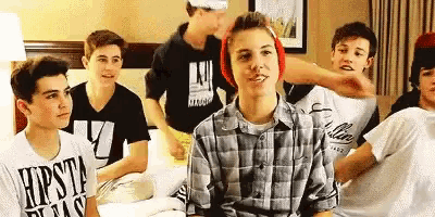 a group of boys are sitting on a bed in a room .
