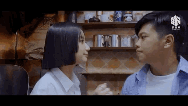 a man and a woman are looking at each other in front of a shelf with coca cola cans on it .