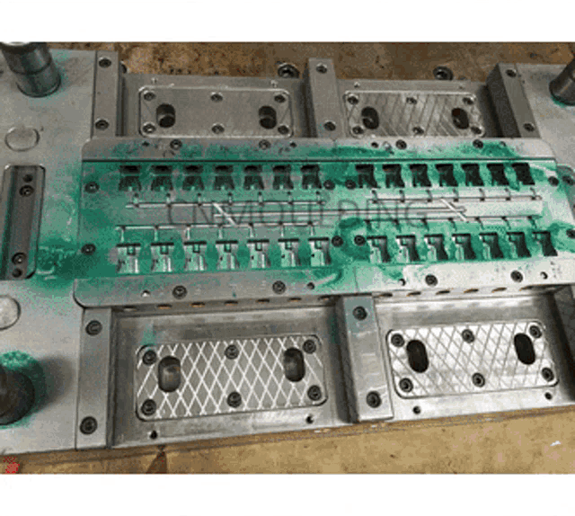 a metal mould with green paint on it that says ' lmc ' on it