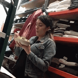 a woman in a denim jacket is holding a bowl of food in a store