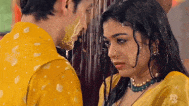 a man and a woman are standing in the rain and the woman is covered in yellow powder