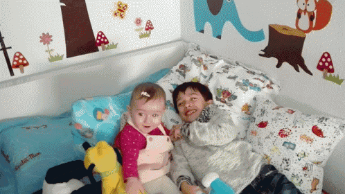 a boy and a girl are laying on a bed with a pillow that says ' little blue '
