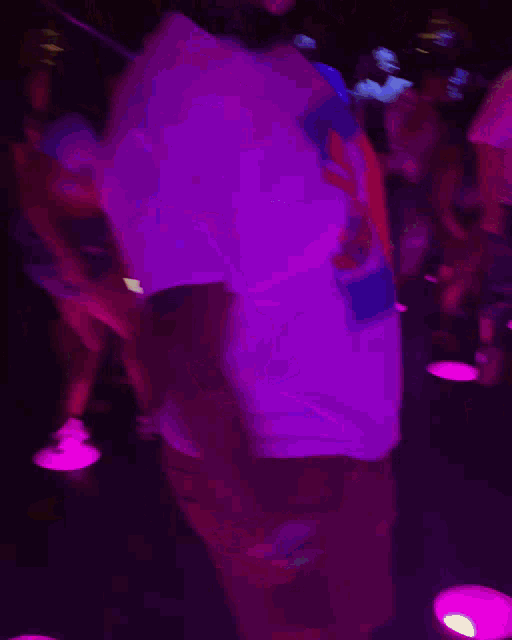 a man in a white shirt is dancing in a crowded room