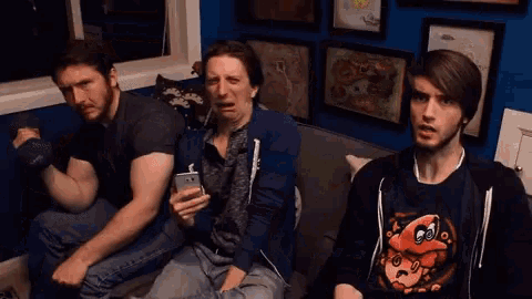 two men are sitting on a couch with one wearing a shirt that says pac man