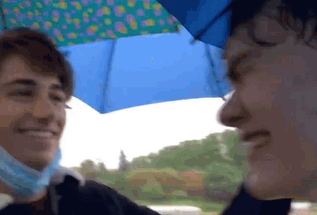 two people are standing under an umbrella and one of them is wearing a mask