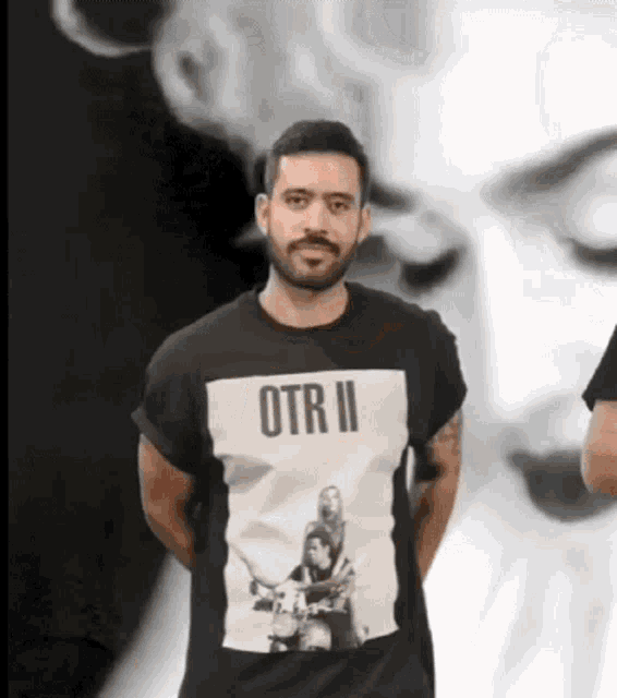 a man with a beard is wearing a black t-shirt that says otrii