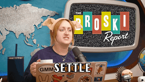 a woman is holding a cup of coffee in front of a microphone in front of a screen that says settle