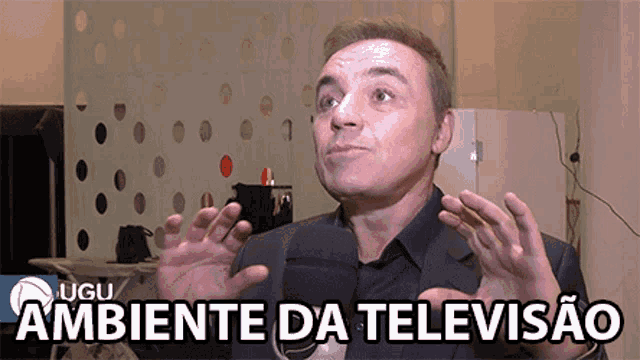 a man in a suit talks into a microphone with the words ambiente da televisao above him