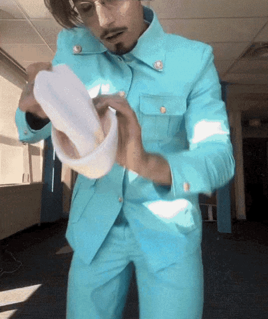 a man in a light blue suit is holding a plastic container