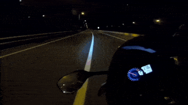 a motorcycle is driving down a highway at night and the speedometer reads 28