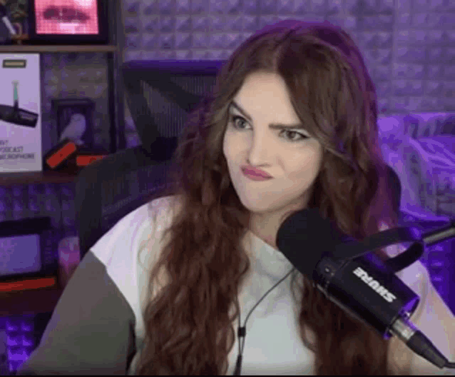 a woman is making a funny face while sitting in front of a microphone in a recording studio .