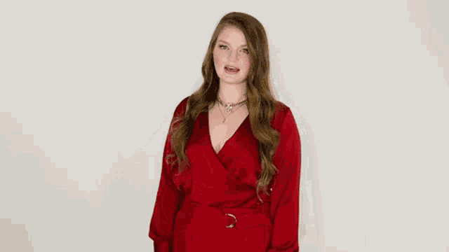 a woman in a red dress is making a rude gesture with her middle finger .