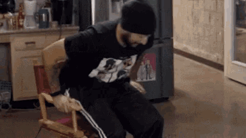 a man in a black hat is sitting in a director 's chair .