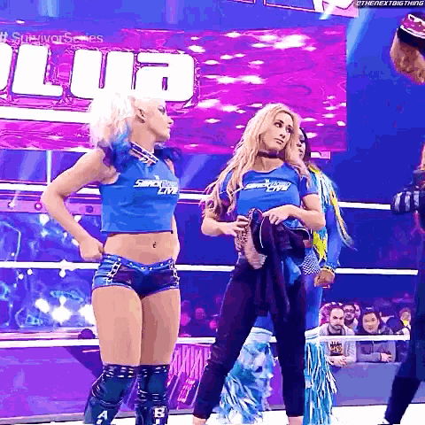 a group of women are standing in a wrestling ring and one of them is wearing a shirt that says smackdown live