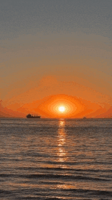 a sunset over the ocean with a boat in the distance