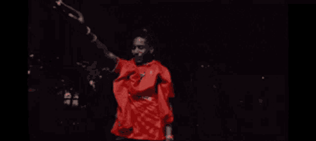 a man in a red shirt is dancing with his arms outstretched
