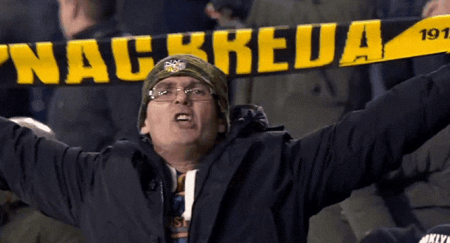 a man wearing a hat and glasses holds up a scarf that says nachreda