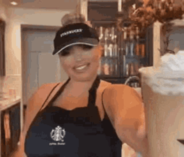 a woman wearing an apron and a hat is holding a milkshake in her hand .