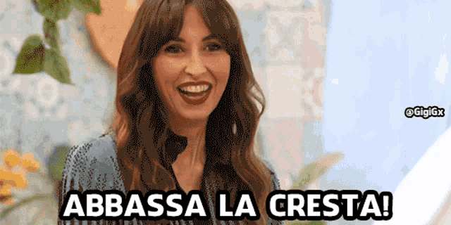a woman is smiling with the words abbassa la cresta written below her