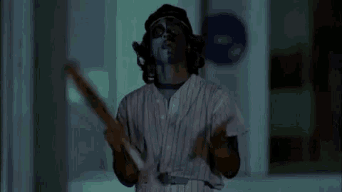a man in a baseball uniform with face paint on his face is holding a baseball bat .