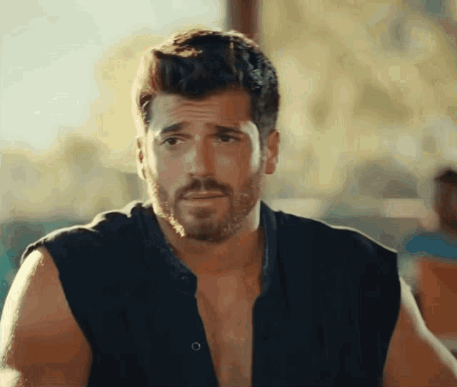 a man with a beard is wearing a black shirt without a shirt