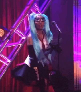 a woman with blue hair is singing into a microphone on stage .