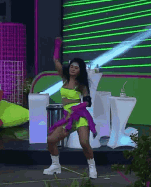a woman in a neon yellow outfit is dancing on a stage