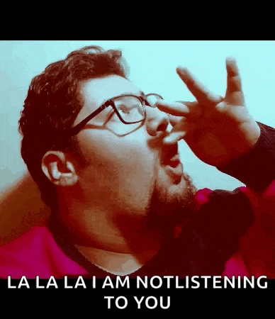 a man with glasses is making a funny face and says la la la i am not listening to you .