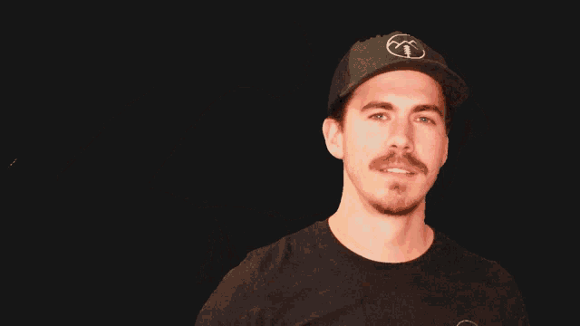 a man wearing a black hat and a black shirt is flexing his arm