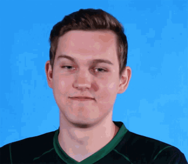 a young man wearing a black shirt with a green collar makes a funny face