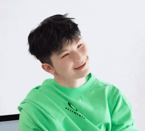 a young man wearing a green shirt that says vetements on it