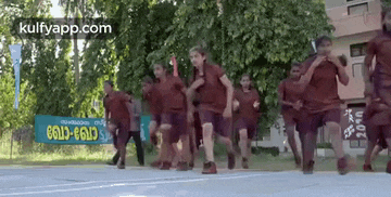 a group of children are running in a line on a basketball court .