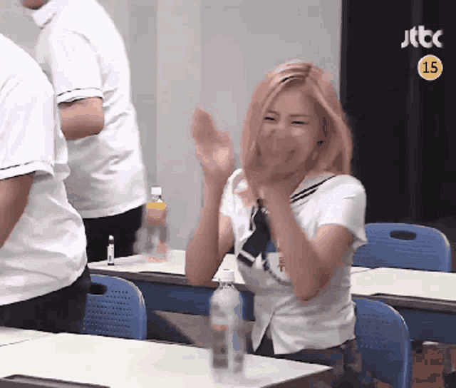 a girl with pink hair is clapping in front of a jtbc sign