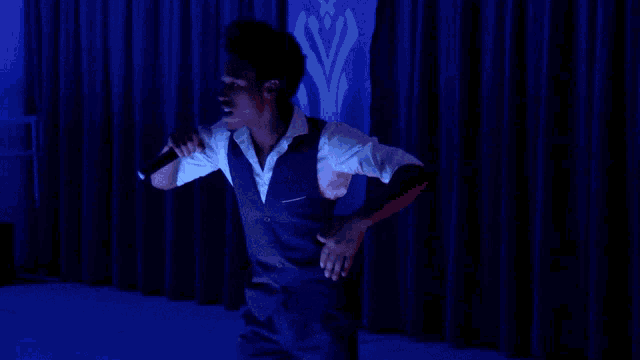 a man singing into a microphone with a blue background