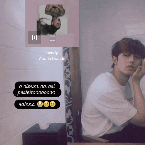 a man sitting in front of a needy ariana grande album cover