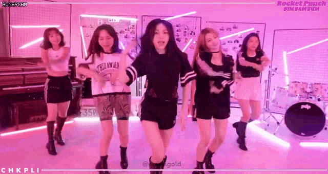 a group of girls are dancing in front of a drum set with the words rocket punch in the corner