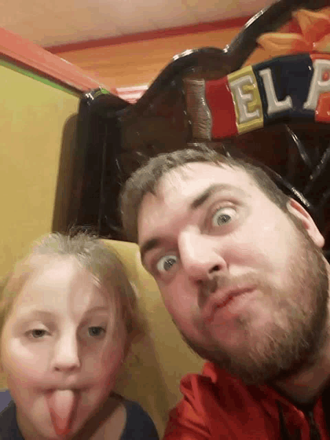 a man with a beard and a little girl sticking their tongues out in front of a sign that says el