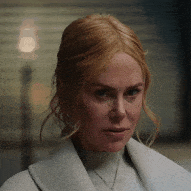 a close up of a woman 's face wearing a white coat .