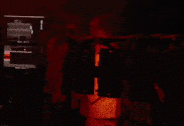 a man wearing sunglasses stands in a dark room with a red background