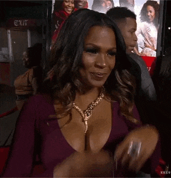 a woman in a very revealing purple dress is smiling and touching her head .