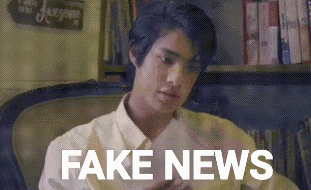 a man sitting in a chair holding a piece of paper with the words fake news written on it