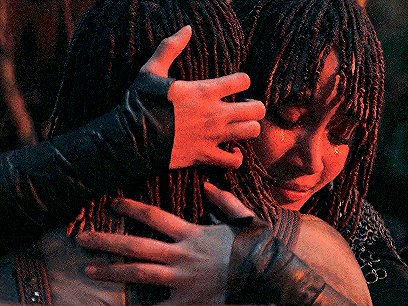 a woman with dreadlocks is hugging another woman who is crying