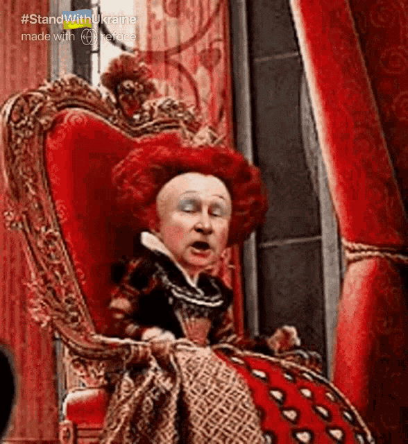 queen of hearts from alice in wonderland sits in a red chair