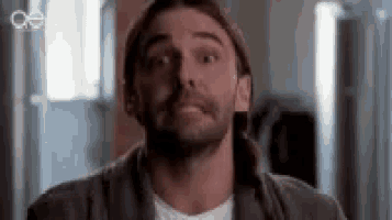 a man with a beard is making a funny face while wearing a hat .